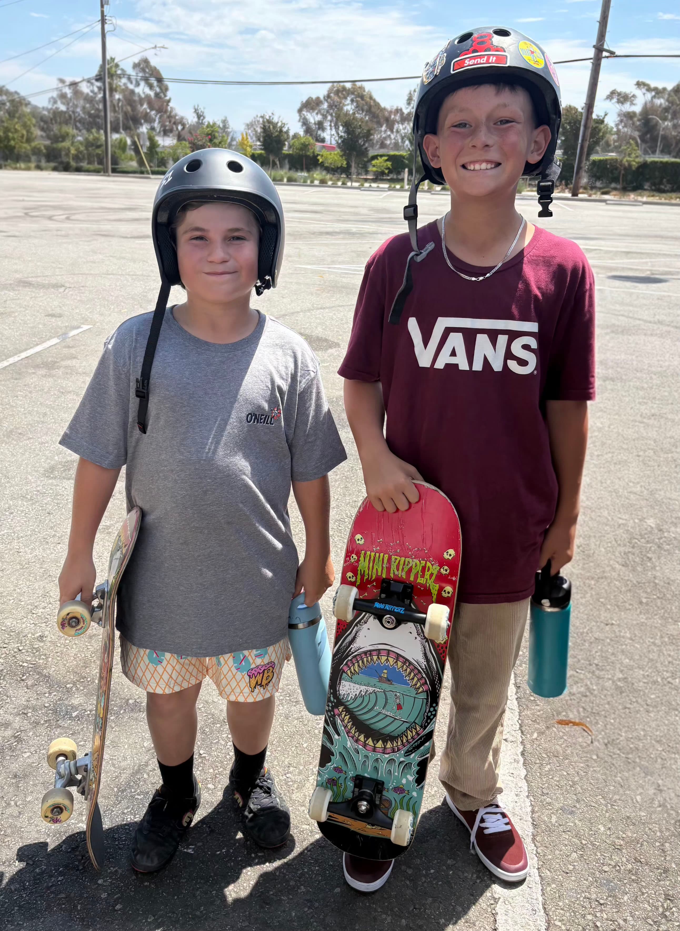 Leah's two sons standing together with their skateboards.